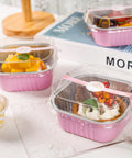 Heavy Duty Square Aluminum Foil Cake Pans 50 Pack Hot Pink 10oz With Secure Snap Lids holding colorful desserts on a table.