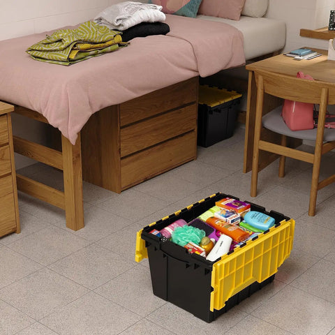 Heavy Duty 12 Gallon Storage Containers With Attached Lids, Stackable Workshop Totes For Garage Organization Setup, Built Like A Tank Plastic Bins In Black And Yellow filled with various items next to a bed.
