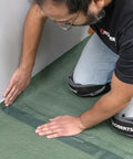 Person applying Easy Peel Overlap Tape on Top Shelf Premium Underlayment One Hundred Square Foot Roll for flooring.