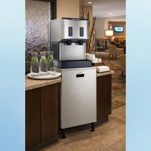 No Drama Countertop Nugget Ice Maker And Water Dispenser with stainless steel finish and push controls, set in a modern lobby.