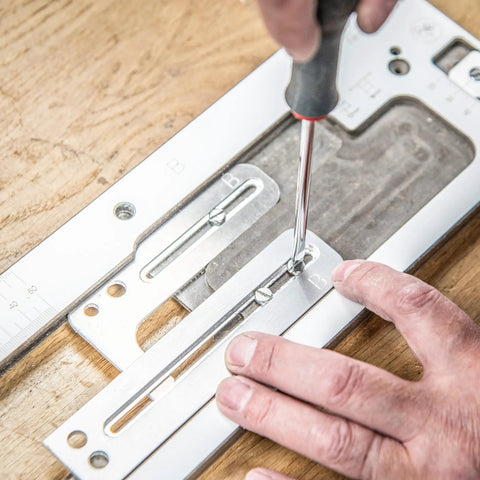 No Fuss Adjustable Door Latch And Strike Plate Router Jig Featuring Knockout Precision with hands adjusting screws on jig.