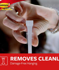 Hand holding Medium Refill Replacement Strips for Damage Free Hanging on small wall hooks, demonstrating adhesive removal.
