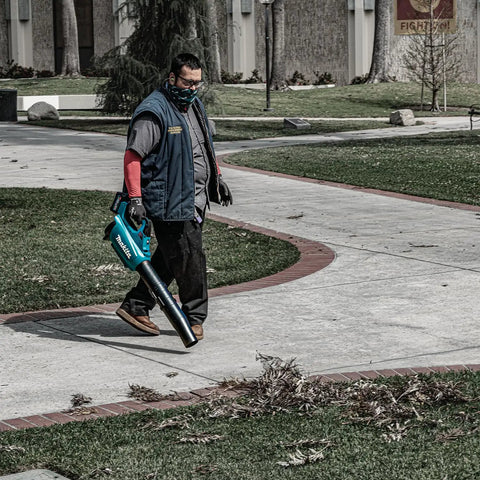 Person operating Top Shelf Brushless Cordless Leaf Blower Featuring Smooth Trigger Cruise Control And Boost Mode on a sidewalk.