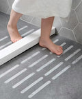 Person stepping on Grippy Non Slip Bathtub And Shower Stickers Set 24 Pieces 8 By 0.8 Inch Anti Skid Treads Tape on bathroom floor
