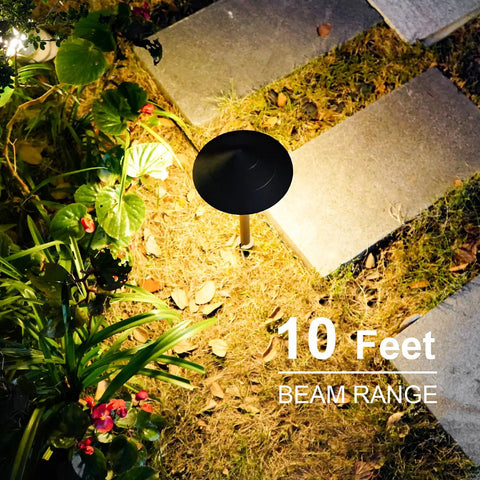 Bronze garden path light from 4 Pack Low Voltage Path Lights Kit With 2W LEDs 100 Lumen Warm White 2700K, illuminating a stone walkway.