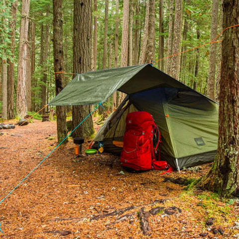 Beefy Weatherproof Canvas Tarp For Outdoors Highly Durable Waterproof Tarpaulin Shelter in forest campsite over red backpack