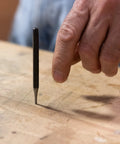 16 Piece Punch And Chisel Set With Pin Punches And Center Punches For Metalwork, showing a hand using a center punch on wood.