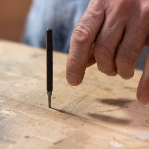 16 Piece Punch And Chisel Set With Pin Punches And Center Punches For Metalwork, showing a hand using a center punch on wood.