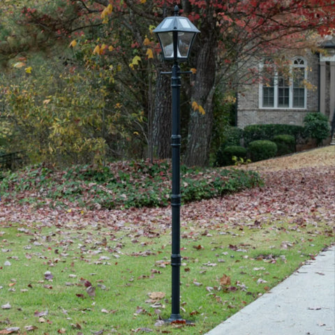 Baytown II Outdoor Solar Lamp Post with EZ Anchor Kit, Black Finish, on a grassy garden pathway, surrounded by autumn leaves.