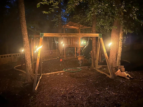 Outdoor swingset with torches at night, featuring Heavy Duty Hammock Chair Spring 1100Lbs 4 Inch Hook For Porch Swing Outdoor Patio.
