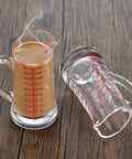 Glass Measuring Cup 5 Oz 150 Ml Shot Glass With V Spout And Insulated Handle shown filled and empty on wooden surface