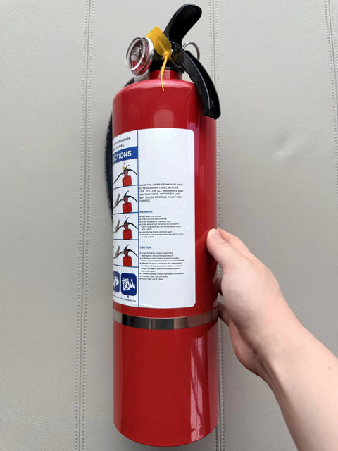 Four Pack Five Lb Abc Dry Chemical Fire Extinguisher Set Featuring No Fuss Quick Release Pin, red steel unit held in hand.