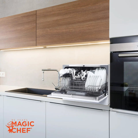Real Deal Compact Countertop Dishwasher For Modern Kitchens Clean Cycle For Six Place Settings With A Durable Stainless Steel Tub and Super Chill Quiet Operation No Sweat Push Button Controls Space Savvy Portable Mini Washing Machine In Fresh White shown in use with plates and utensils inside.