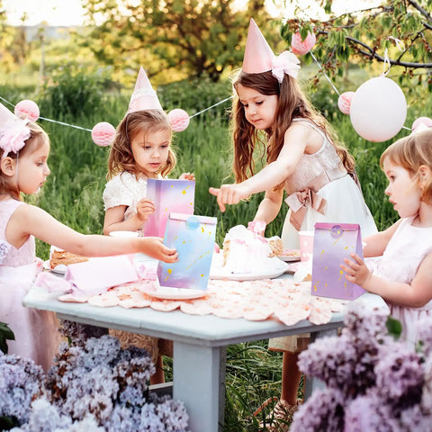 Children at a party with Tie Dye Party Favor Bags With 36 Stickers 30 Pack Mermaid Unicorn Themed Goodie Bags on a table.
