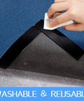 Hand using 32 Piece Rug Gripper Set Anti Slip Corner Pads And Washable Sticky Protectors For Hardwood Floors And Tile, 16 Round And 16 Oblong Pads, Black, Keeps Rugs From Sliding And Shifting On Any Surface under a blue rug.