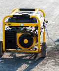 Portable generator with yellow frame and wheels on pavement background
