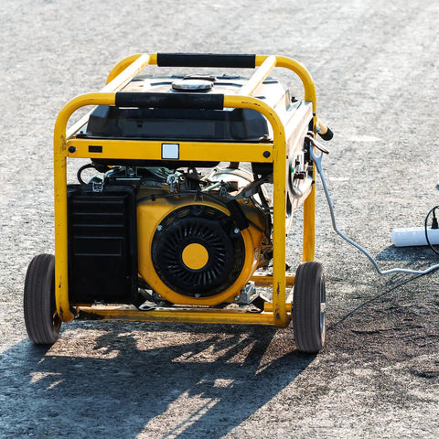 Portable generator with yellow frame and wheels on pavement background