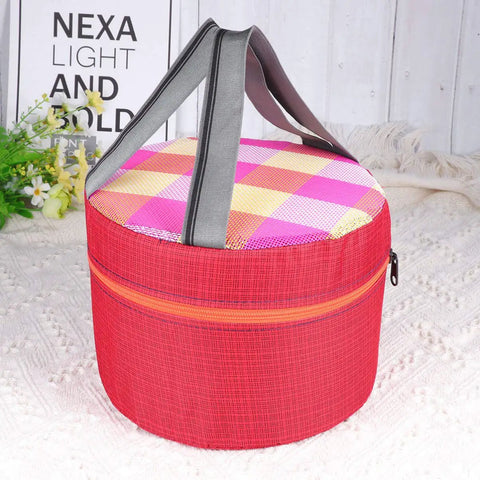 Round insulated lunch bag with red exterior, checkered pink and orange lid, and black handles on white background