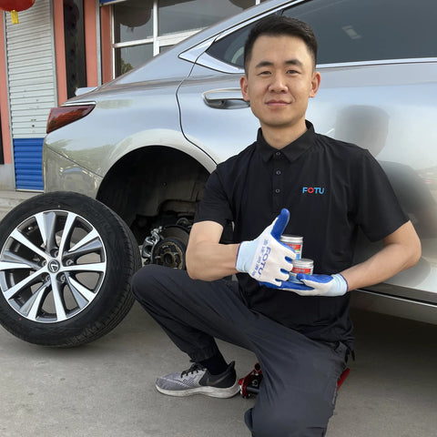Front view: FOTU brake caliper grease cans held by mechanic beside silver car with wheel removed