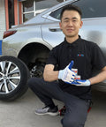 Mechanic holding Complete Brake Caliper Grease Kit with 661 Guide Pin Grease, 561 Anti Squeal, and 361 High Temp Copper Anti Seize near car