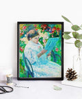 Framed art print of a woman in a garden reading, displayed on a table with decorative items, like pine cones and leaves.