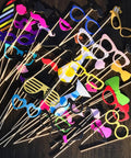 Colorful photo booth props on sticks including glasses, mustaches, and lips for fun party decor.