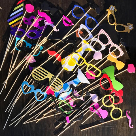 Colorful photo booth props on sticks including glasses, mustaches, and lips for fun party decor.