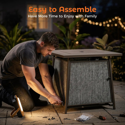 Man assembling 50,000 BTU Propane Fire Pit Table, 28 Inch Square, 2 In 1 Outdoor Fire Pit with Lid, on patio at night.