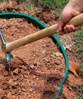Person using Heavy Duty Gardening Pick Axe With Wooden Handle And Stainless Steel Mattock on red clay soil