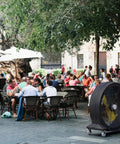 Kick Serious Heat To The Curb With This Heavy Duty 42 Inch Portable Barrel Fan pumping 11044 cfm cooling a busy outdoor cafe.
