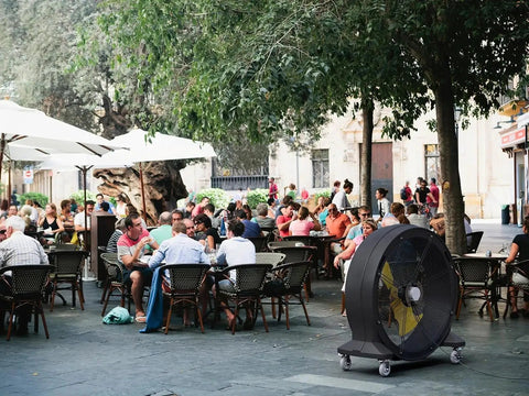 Kick Serious Heat To The Curb With This Heavy Duty 42 Inch Portable Barrel Fan pumping 11044 cfm cooling a busy outdoor cafe.