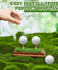 2 In 1 Golf Ball Display Case With Clear Acrylic Cube Stand, wood base and turf mat, shown on grass with golf balls.