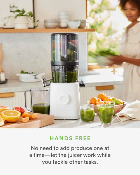 Nama J2 Cold Press Juicer Hands Free White Self Feeding Hopper For Fruits And Vegetables Easy Cleanup Low Speed Masticating Extractor Machine on kitchen counter with fresh produce.