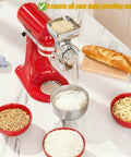 Grain mill attachment for KitchenAid stand mixer; red all-metal construction mounted; bowls of flour, grains, pasta.