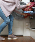 Person loading laundry into machine, highlighting Smart WiFi Water Leak Detector With Real Time Text And Email Alerts, no hub needed