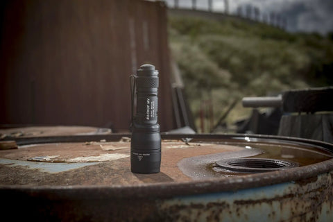 Dual Output LED Backup Flashlight With MaxVision Beam Technology for Everyday Carry resting on a rusted barrel