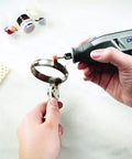 Person using All-Purpose Rotary Tool Accessory Kit With 110 Pieces Including Carving Bit Sanding Drums Grinding Stones Cutting Discs And A Storage Case Gray Ideal For DIY Projects And Home Improvement Tasks to polish metal jewelry ring.