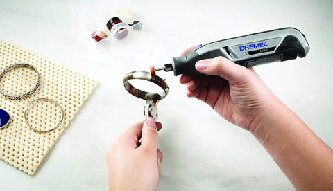 Person using All-Purpose Rotary Tool Accessory Kit With 110 Pieces Including Carving Bit Sanding Drums Grinding Stones Cutting Discs And A Storage Case Gray Ideal For DIY Projects And Home Improvement Tasks to polish metal jewelry ring.