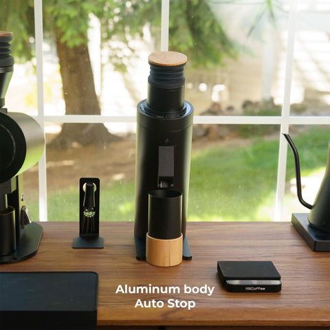 Solid Single Dose Coffee Grinder Featuring 63Mm Red Titanium Conical Burrs And Plasma Ionizer To Crush Beans Sick Flat And Eliminate Static Drama For Flawless Pulls In Sleek Black Housing on wooden counter with auto stop feature.