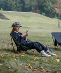 Person relaxing outdoors in Ultralight Low Profile Camping Folding Chair With Side Pocket And Carry Bag 7.5 Inch Seat Height
