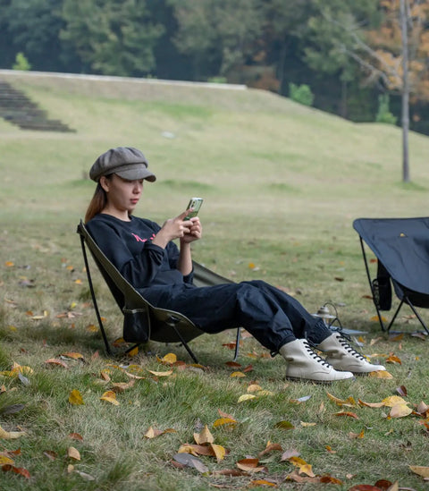 Person relaxing outdoors in Ultralight Low Profile Camping Folding Chair With Side Pocket And Carry Bag 7.5 Inch Seat Height