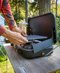 Setting up 3 In 1 Propane Camping Stove With Cast Iron Grill And Griddle, 24,000 BTU Dual Adjustable Burners at a campsite.
