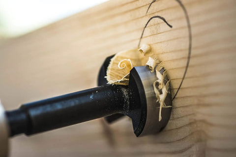 Forstner drill bit in wood, showcasing precise drilling with shavings, part of a five-piece set made of high-speed steel.