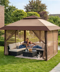 Family relaxing under Easy Setup 13x13 Pop Up Gazebo with Wheeled STO-N-Go Cover Bag in beige and coffee color, backyard setting.