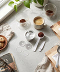 Double Filter Stainless Steel Reusable Coffee Pods With Fast Twist Screw Switch For Custom Ground Roasts displayed on a countertop with coffee, cookies, and brewing accessories.
