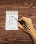 Person using pen on Pro Grade 20 Pack Industrial Equipment Inspection Card Set With Sleeves, PVC card on wooden table.