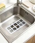 Hair Drain Stickers 100Pcs Disposable Self Adhesive on stainless steel sink, featuring dense mesh filtration and self-adhesive backing.
