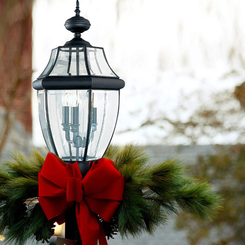 Lancaster Outdoor Post Lantern Three Light Outdoor Fixture With Slick Black Finish 24 Inch Height adorned with red bow