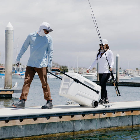 Couple using MaxCold Glide 110 Qt Insulated Rolling Cooler With Soft Ride Wheels on dock with telescoping handle.