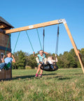 Children playing on Cedar Wood Swing Set With Wave Slide And Elevated Clubhouse Play Kitchen And Picnic Area Belt And Web Swings